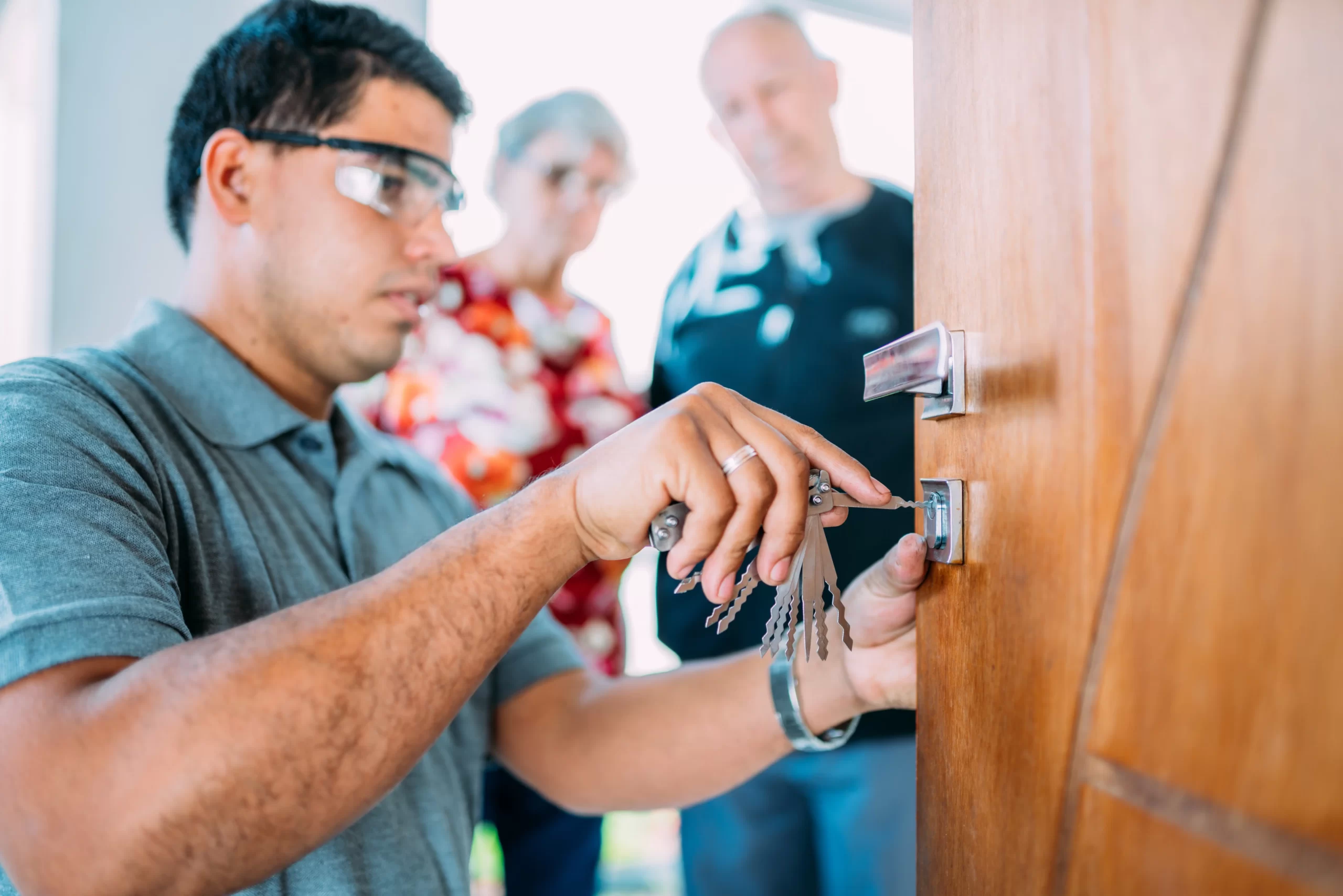 primer-plano-manos-masculinas-reparar-o-instalar-cerradura-puerta-metal-pareja-mayor-fondo